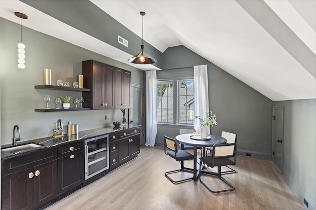 kitchen featuring hanging light fixtures, sink, beverage cooler, and dark brown cabinets