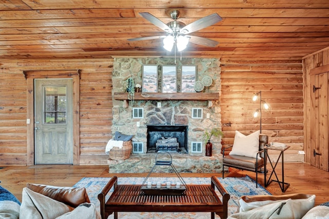 living room with hardwood / wood-style floors, a healthy amount of sunlight, a stone fireplace, and wood ceiling