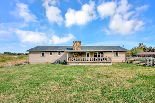 rear view of house featuring central AC unit and a yard