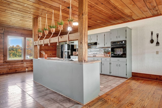 kitchen with brick wall, sink, black appliances, wooden ceiling, and hanging light fixtures