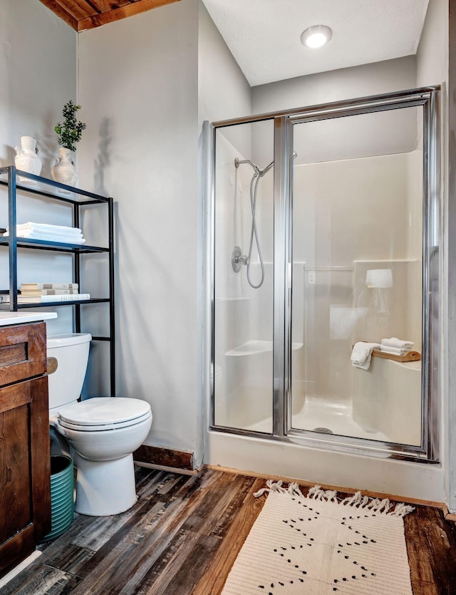 bathroom with toilet, a shower with door, vanity, and hardwood / wood-style flooring