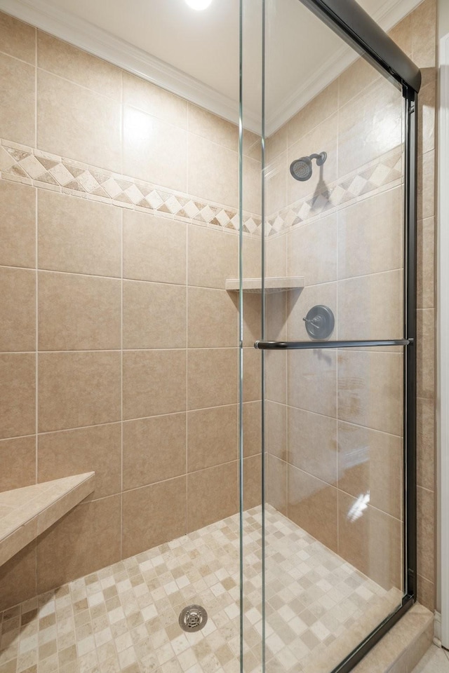 bathroom with crown molding and a shower with shower door