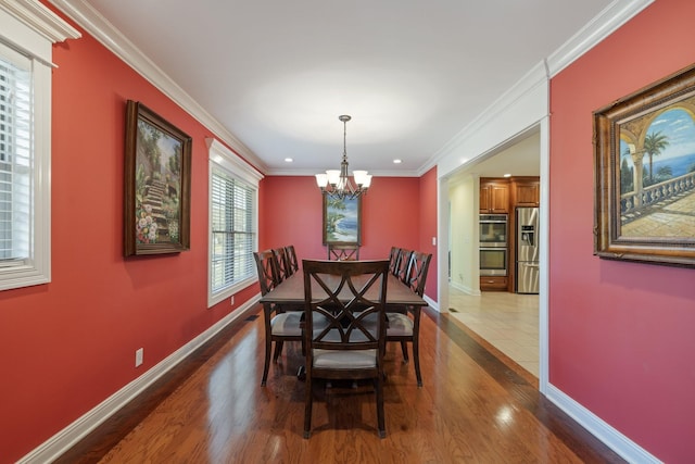 dining room featuring hardwood / wood-style flooring, an inviting chandelier, and crown molding