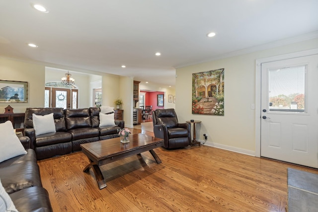 living room with light wood-type flooring, crown molding, and a notable chandelier