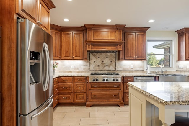 kitchen featuring tasteful backsplash, light stone counters, sink, and stainless steel appliances