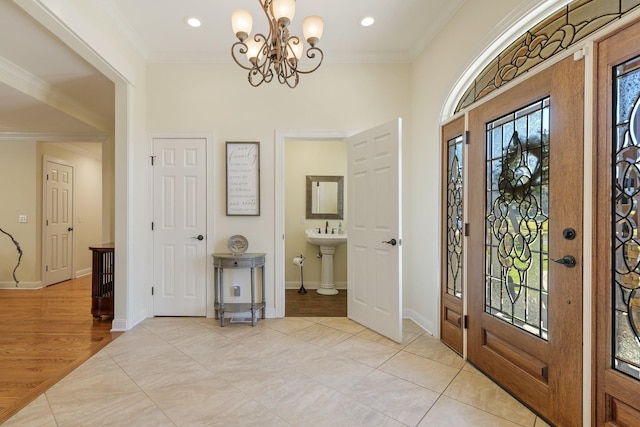 tiled foyer entrance featuring crown molding, sink, and a notable chandelier