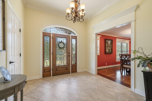 entrance foyer with a notable chandelier, ornamental molding, and light tile patterned floors