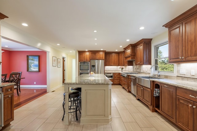 kitchen featuring backsplash, sink, appliances with stainless steel finishes, a kitchen island, and a kitchen bar