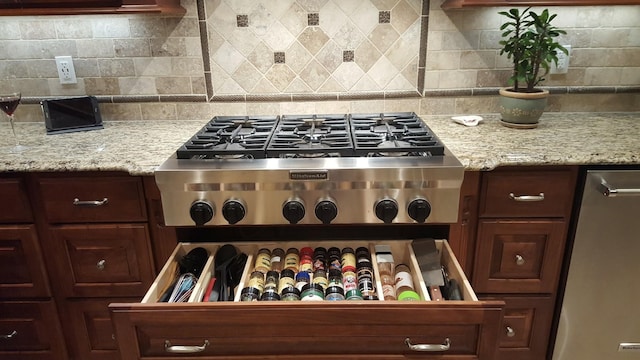 kitchen featuring decorative backsplash, light stone countertops, and stainless steel appliances