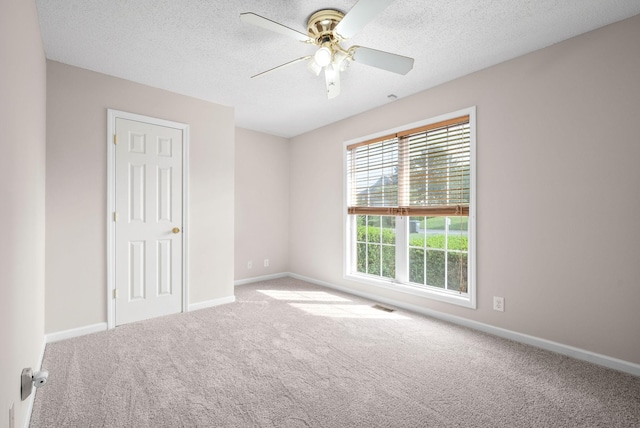 unfurnished room with a textured ceiling, carpet floors, and ceiling fan