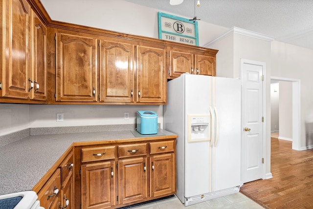 kitchen featuring white refrigerator with ice dispenser, range, a textured ceiling, and crown molding