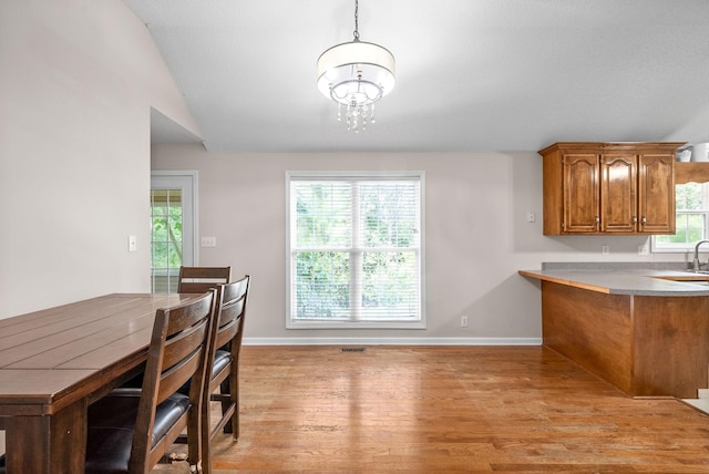 dining space with light hardwood / wood-style flooring, lofted ceiling, and an inviting chandelier