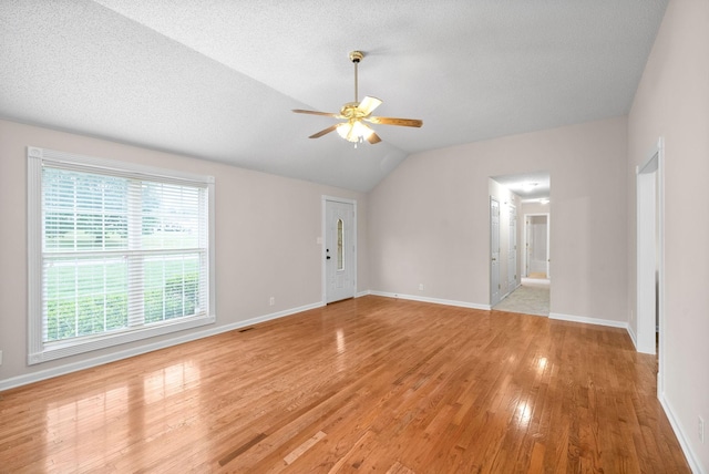 spare room with ceiling fan, light hardwood / wood-style flooring, a wealth of natural light, and vaulted ceiling