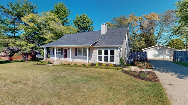 view of front of house featuring a front yard, a garage, covered porch, and an outbuilding