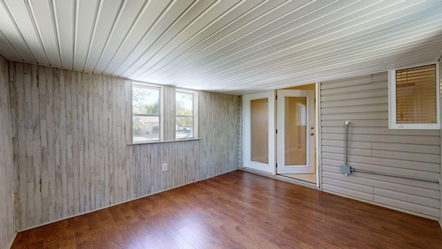 empty room featuring wood-type flooring, wooden ceiling, and wood walls