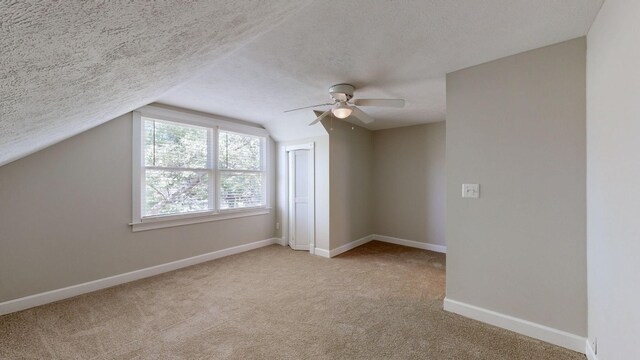 bonus room with a textured ceiling, light carpet, and lofted ceiling