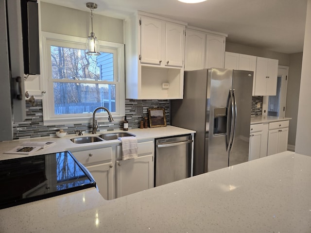 kitchen with hanging light fixtures, tasteful backsplash, white cabinets, appliances with stainless steel finishes, and sink