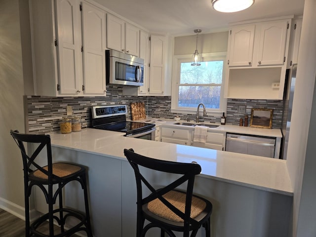 kitchen with sink, white cabinets, a kitchen breakfast bar, and appliances with stainless steel finishes