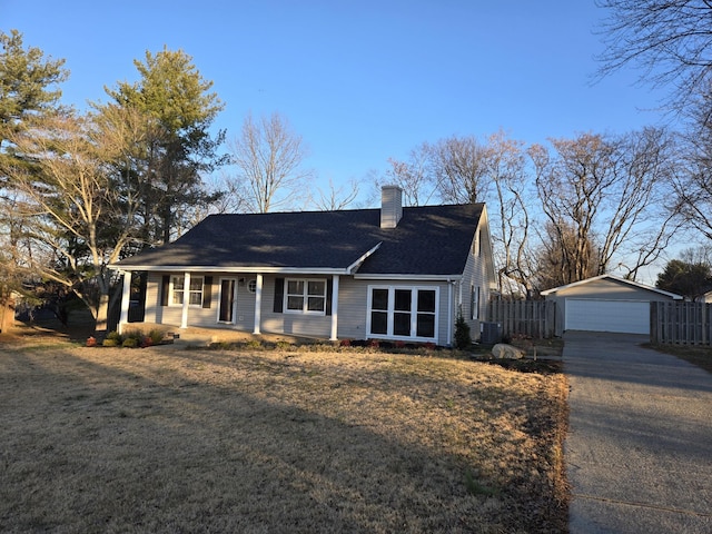 ranch-style house featuring covered porch, a garage, cooling unit, a front yard, and an outdoor structure