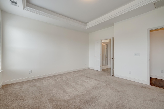 unfurnished room featuring light colored carpet, crown molding, and a tray ceiling