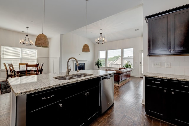 kitchen featuring a center island with sink, dishwasher, sink, and hanging light fixtures