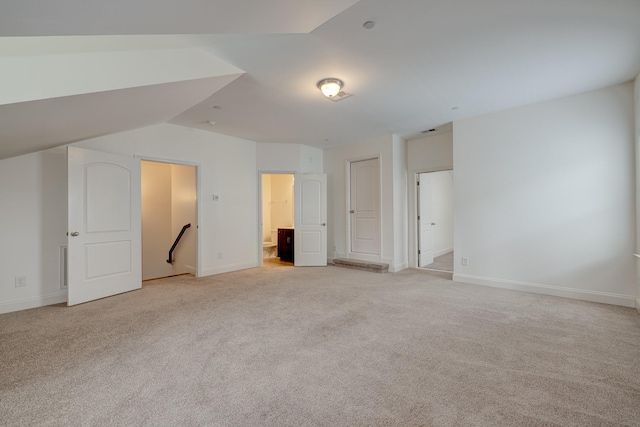 interior space featuring lofted ceiling, light carpet, and ensuite bath