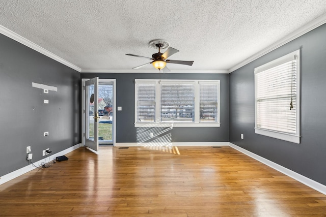 empty room with a wealth of natural light, ceiling fan, hardwood / wood-style flooring, and ornamental molding