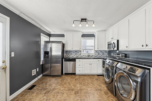 washroom featuring rail lighting, a textured ceiling, crown molding, sink, and washing machine and clothes dryer