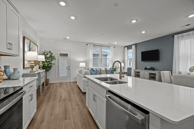 kitchen with appliances with stainless steel finishes, an island with sink, white cabinetry, and sink