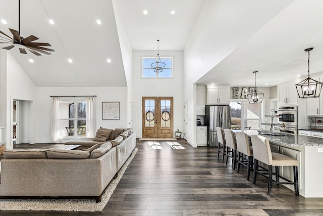 living room featuring ceiling fan, french doors, dark hardwood / wood-style floors, and a high ceiling