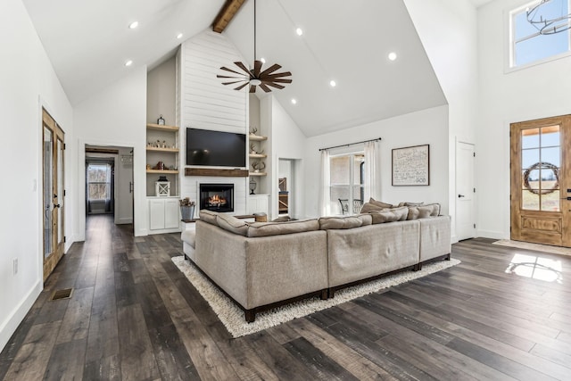 living room featuring beamed ceiling, a large fireplace, high vaulted ceiling, and built in features