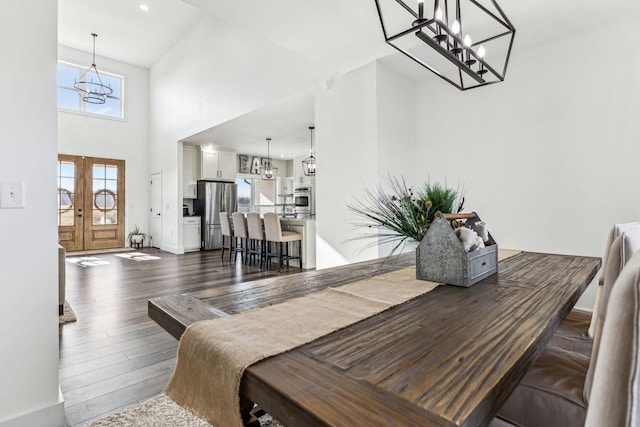 dining space with french doors, a towering ceiling, and dark hardwood / wood-style floors