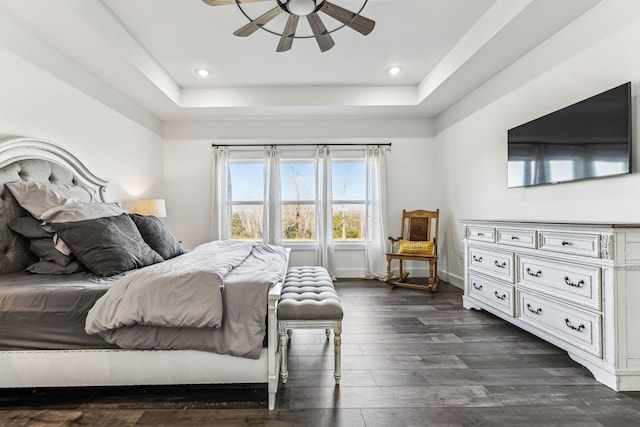 bedroom with dark hardwood / wood-style flooring, a raised ceiling, and ceiling fan