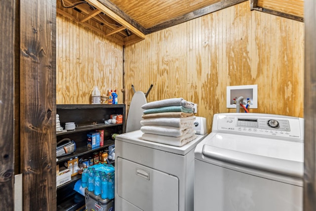 washroom with washing machine and clothes dryer and wood walls