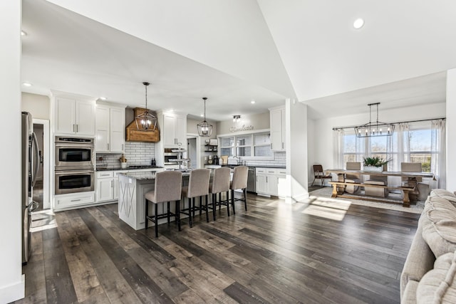 kitchen with white cabinetry, dark stone counters, decorative light fixtures, a breakfast bar area, and a kitchen island