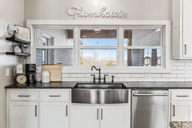 kitchen featuring dishwasher, backsplash, dark stone counters, sink, and white cabinetry