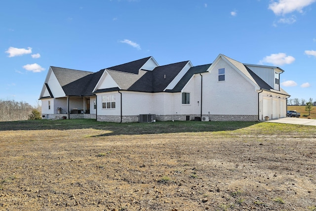 back of house featuring a garage, a yard, and central AC