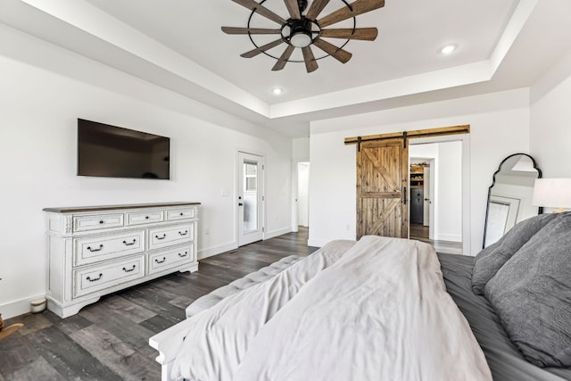 bedroom featuring ceiling fan, a barn door, a raised ceiling, and dark hardwood / wood-style flooring