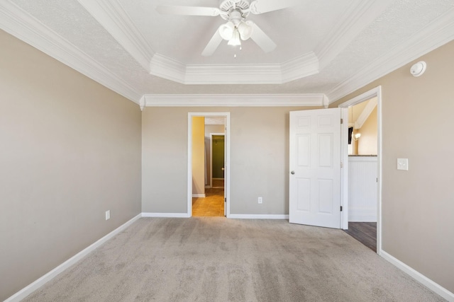 unfurnished bedroom featuring ceiling fan, crown molding, light carpet, and a tray ceiling