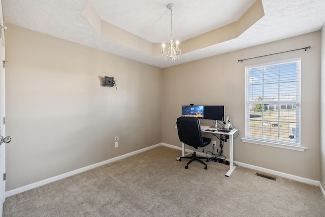 carpeted home office with a raised ceiling, a textured ceiling, and an inviting chandelier