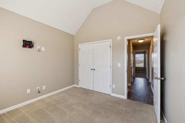 unfurnished bedroom with carpet flooring, vaulted ceiling, and a closet