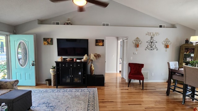 living room with ceiling fan, light hardwood / wood-style floors, and vaulted ceiling