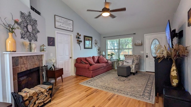 living room featuring a tiled fireplace, ceiling fan, light hardwood / wood-style floors, and lofted ceiling