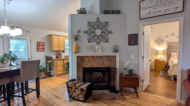 living room featuring a tiled fireplace, light hardwood / wood-style flooring, and an inviting chandelier