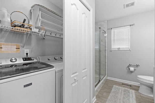 clothes washing area with light hardwood / wood-style flooring and washing machine and clothes dryer