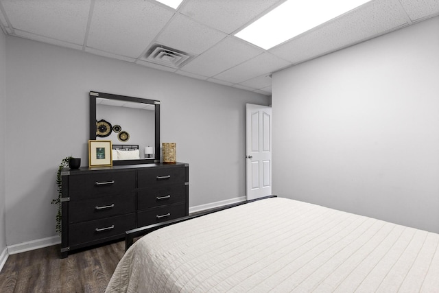 bedroom with a paneled ceiling and dark hardwood / wood-style flooring