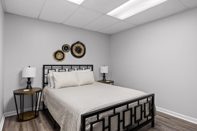 bedroom featuring dark wood-type flooring and a drop ceiling