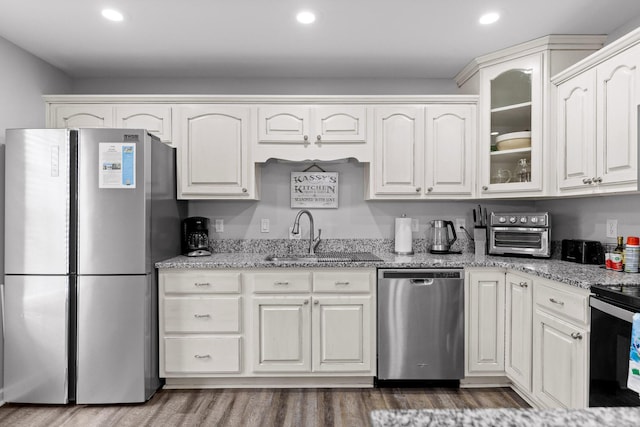 kitchen featuring stainless steel appliances, light stone countertops, sink, and white cabinets