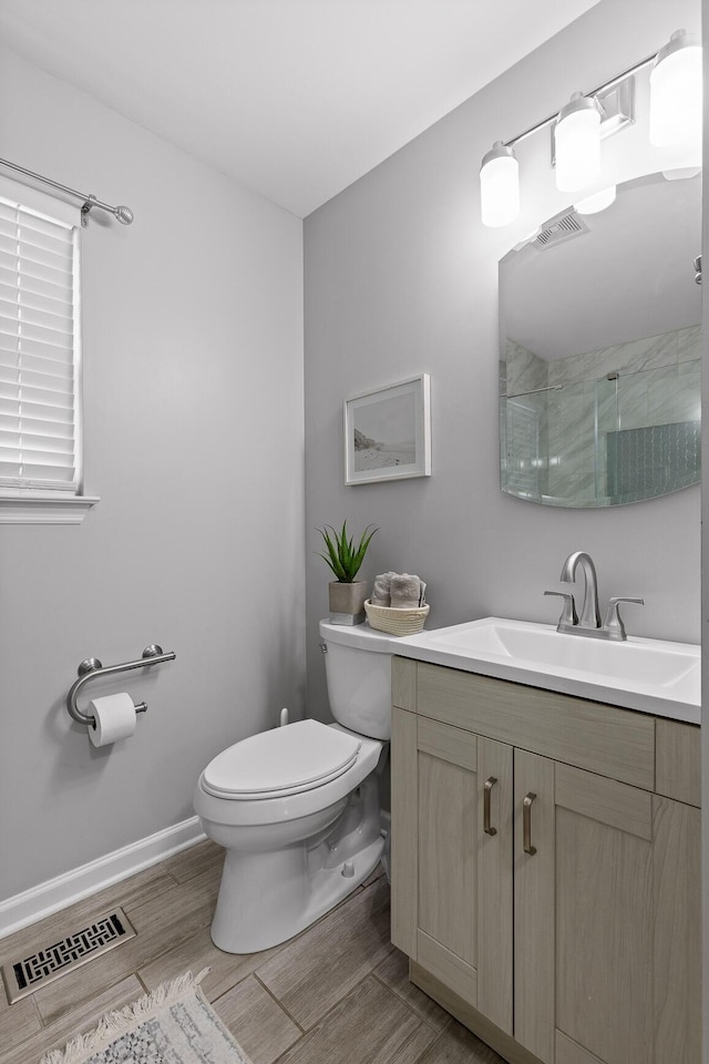 bathroom with vanity, toilet, and a shower with shower door