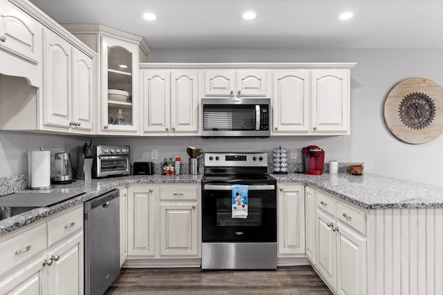 kitchen with light stone countertops, dark hardwood / wood-style floors, white cabinets, and appliances with stainless steel finishes